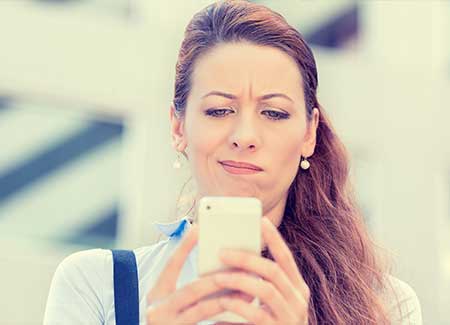 A woman looks at her mobile phone confused