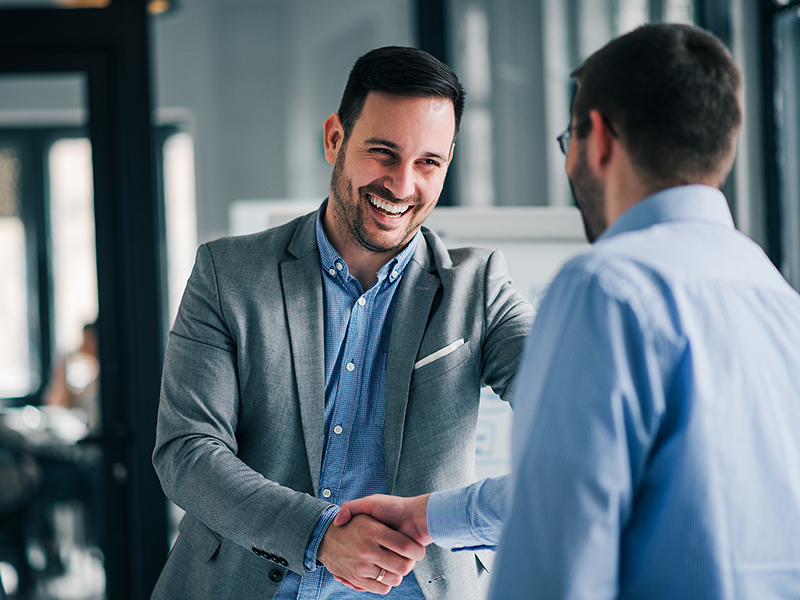 Two business men smile and shake hands