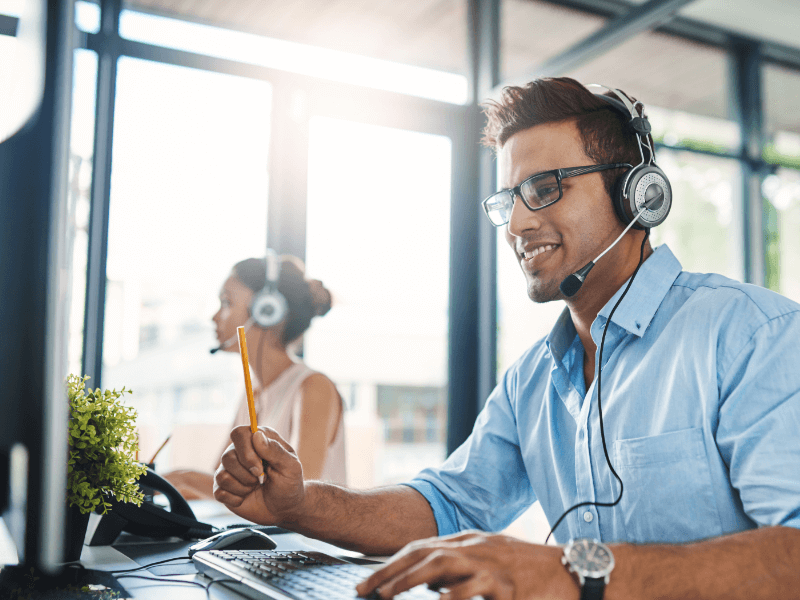 Two people speak to customers on phone headsets