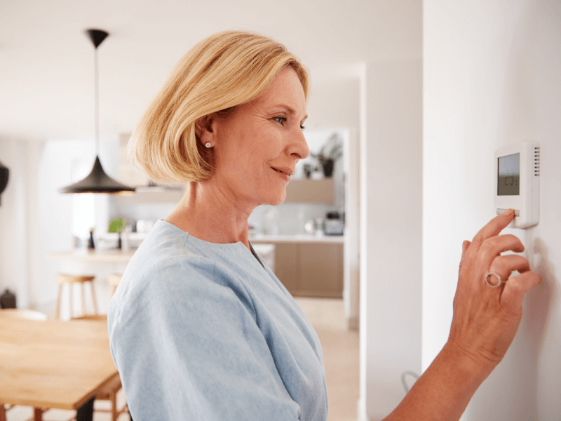 A woman adjusts her thermostat